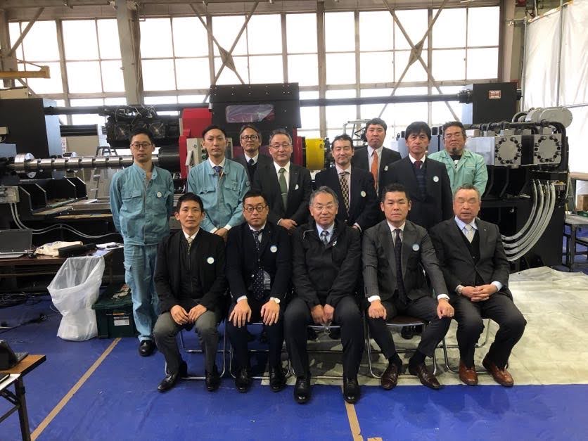 Group photo of participants with the completed friction welding machine in the background.